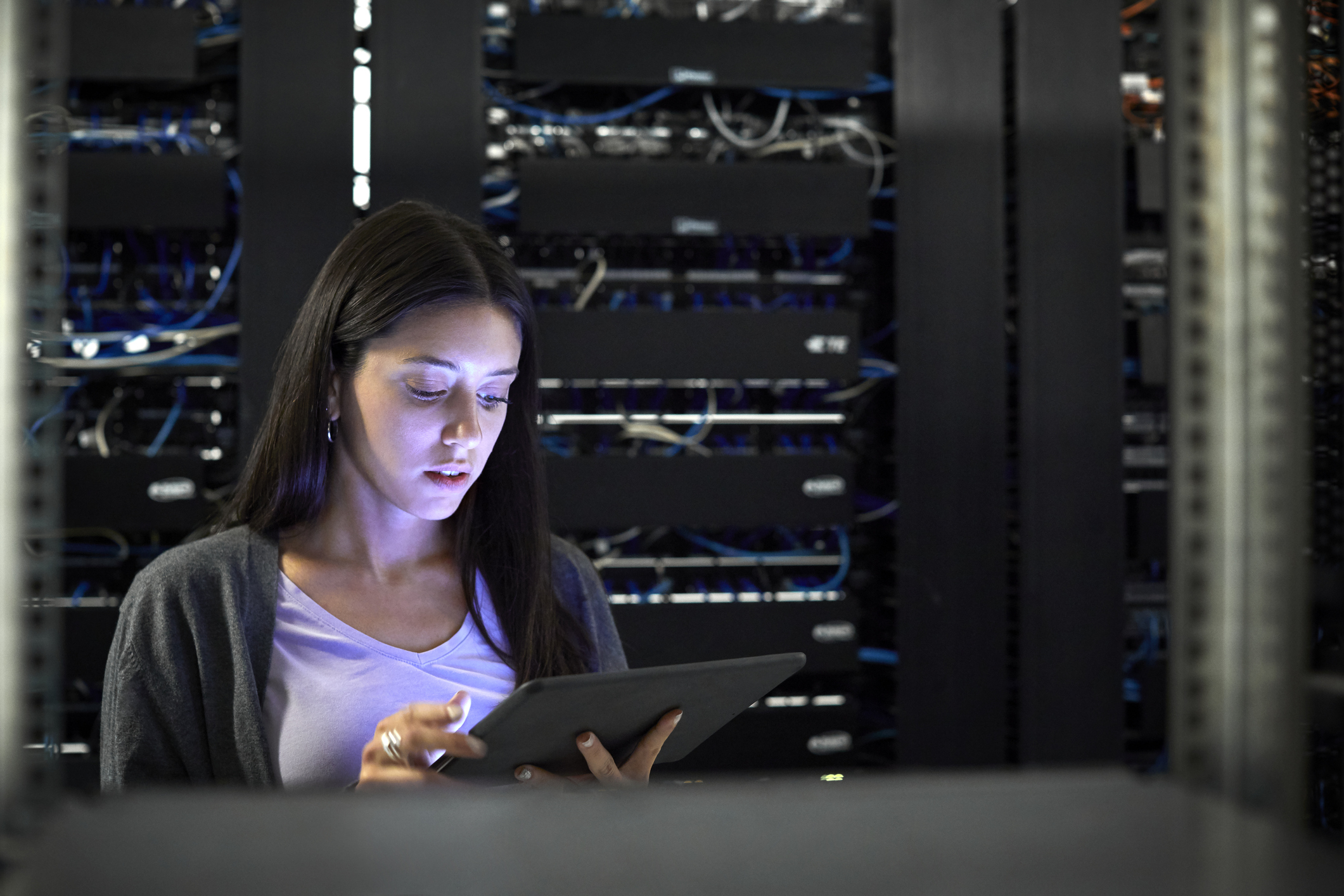 Person using tablet in room with network hardware