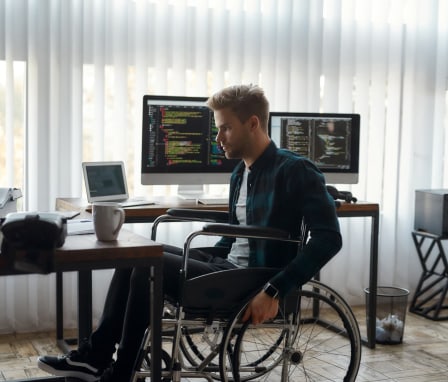 Man in wheelchair beside computer coding