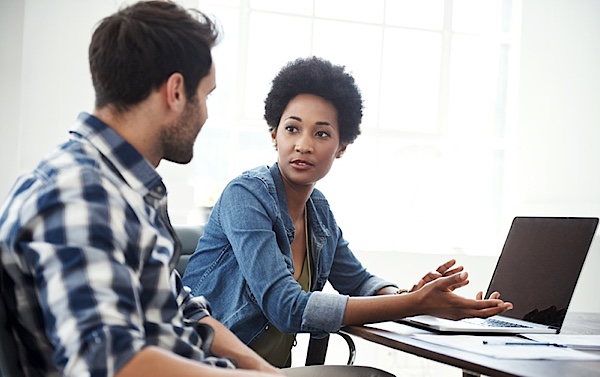 Man and woman talking beside laptop computer