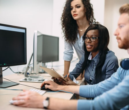 Three programmers looking at a computer screen showing code