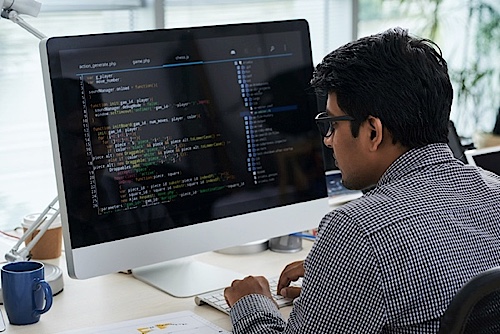 Man editing code on desktop computer