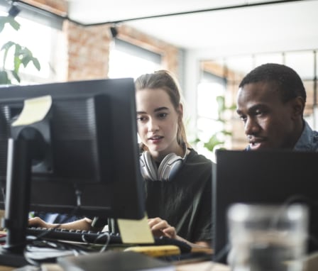 Two computer programmers working on a computer together