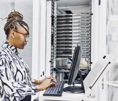 Woman typing on computer with servers in background